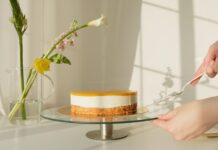 Elegant lemon cheesecake on a stand surrounded by natural flowers. Perfect for celebrations or culinary projects.