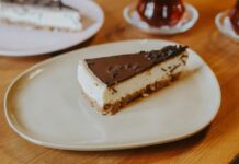 Delectable chocolate-topped cheesecake slice on a plate, perfect for dessert lovers.
