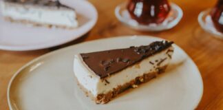 Delectable chocolate-topped cheesecake slice on a plate, perfect for dessert lovers.