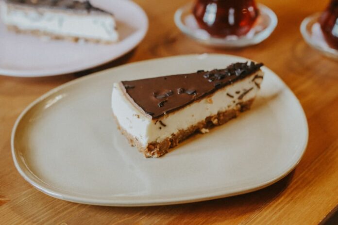 Delectable chocolate-topped cheesecake slice on a plate, perfect for dessert lovers.