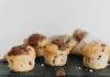 Close-up of four chocolate chip muffins with melted chocolate topping on a slate plate, perfect for food photography.