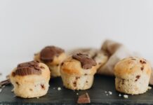 Close-up of four chocolate chip muffins with melted chocolate topping on a slate plate, perfect for food photography.