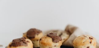 Close-up of four chocolate chip muffins with melted chocolate topping on a slate plate, perfect for food photography.