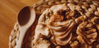 Top view of a freshly baked apple galette on a woven placemat with a wooden spoon beside it.