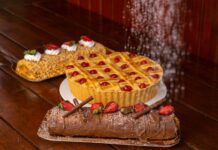 Delicious assortment of pies and cakes topped with fruit on a rustic wooden table.