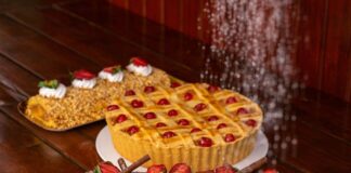 Delicious assortment of pies and cakes topped with fruit on a rustic wooden table.