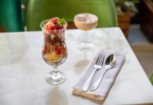 A delicious ice cream sundae with strawberries and a creamy dessert on a white table.