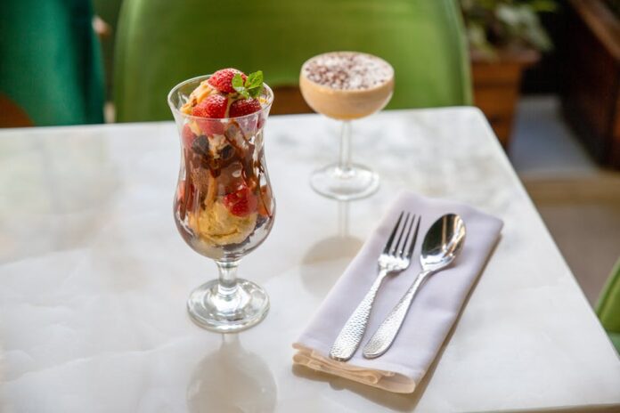 A delicious ice cream sundae with strawberries and a creamy dessert on a white table.