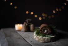 Tronco de Natal com chocolate Chocolate cake roll on a rustic board with bokeh lights, ideal for holiday themes.