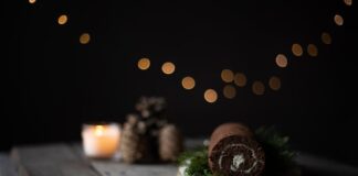 Chocolate cake roll on a rustic board with bokeh lights, ideal for holiday themes.