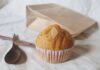 A freshly baked banana muffin with almond slice on a neutral background, ideal for breakfast or a snack.