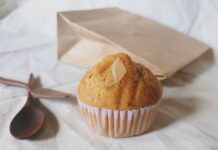 Receita de Bolo de Banana rápido e fofo A freshly baked banana muffin with almond slice on a neutral background, ideal for breakfast or a snack.