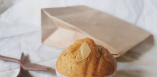 A freshly baked banana muffin with almond slice on a neutral background, ideal for breakfast or a snack.