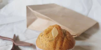 Bolo de Banana rápido e fofo A freshly baked banana muffin with almond slice on a neutral background, ideal for breakfast or a snack.