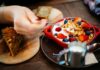 Close-up of a breakfast setting with granola, fresh berries, and a slice of cake.