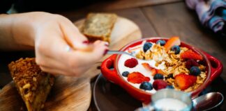 Close-up of a breakfast setting with granola, fresh berries, and a slice of cake.