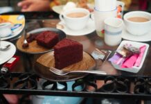 Red velvet cake slices with cups of coffee on a glass table, offering a cozy treat.