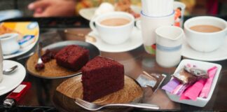 Red velvet cake slices with cups of coffee on a glass table, offering a cozy treat.