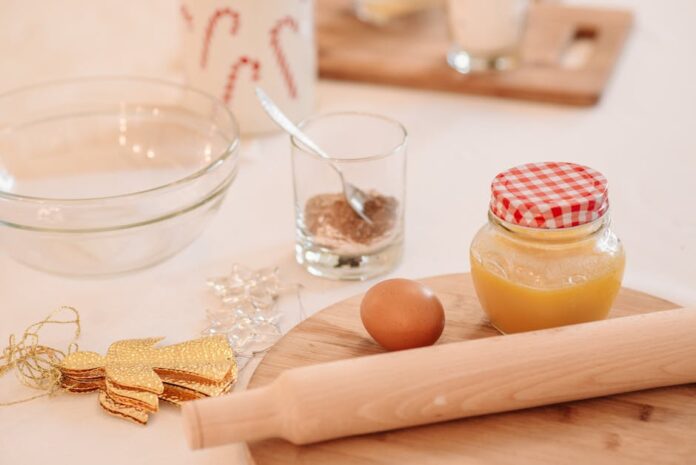 Receita de Coscoroes de Natal com Mel: Delícia na Mesa de Doces A cozy setup with baking ingredients for holiday cookies, featuring a rolling pin, egg, and decorations.