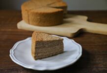 A slice of moist sponge cake on a white plate, perfect for dessert indulgence.