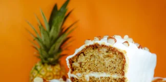 Bolo de Amêndoa laminada com laranja e mel Close-up of a frosted pineapple almond cake on a stand, perfect for dessert lovers.