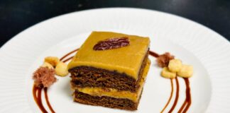 Delicious chocolate cake drizzled with caramel sauce and garnished elegantly on white plate.