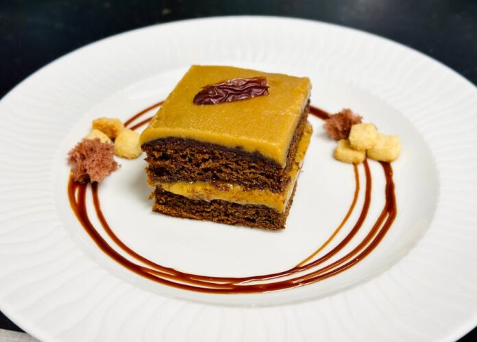 Bolo de Caramelo: Descubra o Segredo da Receita Irresistível! Delicious chocolate cake drizzled with caramel sauce and garnished elegantly on white plate.