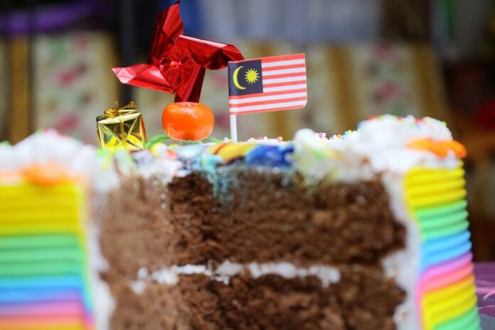 Bolo de Chocolate Caseiro para Tabuleiro: Receita Irresistível! Vibrant rainbow cake with a Malaysian flag, perfect for celebrations and parties.