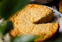 Bolo de Fubá Close-up of a homemade elote cake with a missing slice on a decorative plate.