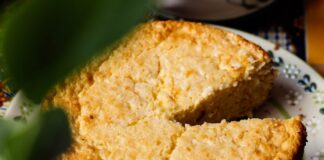 Close-up of a homemade elote cake with a missing slice on a decorative plate.