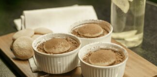 Indulge in homemade tiramisu served in white ramekins on a wooden board. A perfect dessert choice.