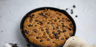 Delicious homemade skillet cookie with chocolate chips and pecans, perfect for dessert indulgence.