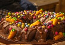 Receita de Bolo de Cenoura fofinho Close-up of a chocolate Bundt cake adorned with colorful candies and frosting, perfect for festive celebrations.