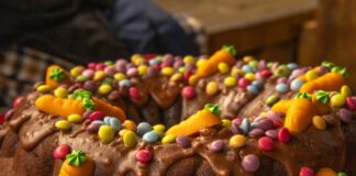 Close-up of a chocolate Bundt cake adorned with colorful candies and frosting, perfect for festive celebrations.