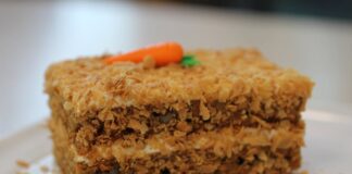 A slice of homemade carrot cake topped with cream frosting, perfect for dessert.