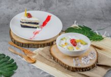 Receita de Bolo de Coco com Iogurte: Sabor irresistível A delectable slice of cake alongside a colorful fruit salad, perfect for dessert lovers.