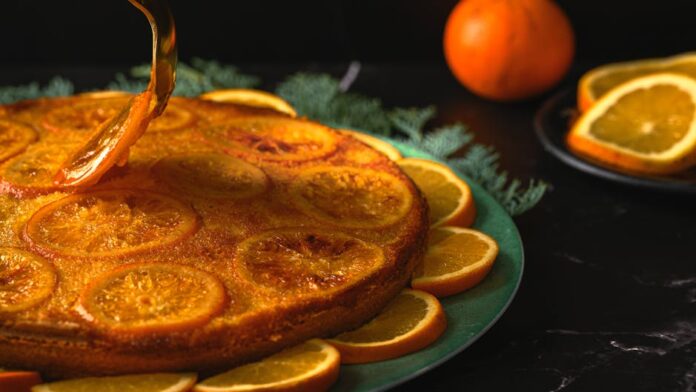 Receita de Bolo de Laranja Econômico: Sabor que Surpreende! A beautifully decorated orange cake with candied orange slices, perfect for dessert lovers.