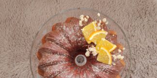 A delicious Bundt cake topped with orange slices and powdered sugar on a textured surface.