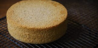 Freshly baked sponge cake resting on a wire cooling rack, perfect for desserts.