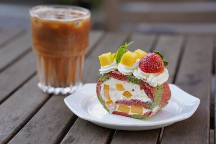 Receita de Bolo Fofo: Acompanhamento Perfeito para Café! Delicious fruit-filled Swiss roll with iced coffee on a wooden table.