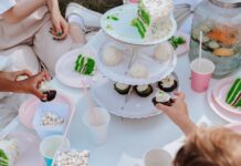 Receita de bolo para lanche das crianças que elas vão adorar Adults and children enjoying a festive garden party with vibrant cakes and cupcakes.