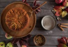 A homemade apple cake surrounded by autumn leaves and spices, top view.