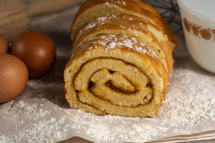 Bolo sem açúcar caseiro simples: descubra o segredo! Tasty homemade Swiss roll cake surrounded by eggs and flour, perfect for baking enthusiasts.