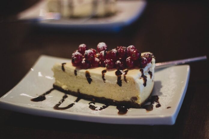 Cheesecake perfeito: descubra o segredo dos chefs! Slice of cheesecake topped with berries and chocolate drizzle on a plate.