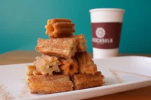 Churros: Descubra segredos e receitas irresistíveis A tempting stack of cinnamon sugar churros with coffee in Azusa, California.