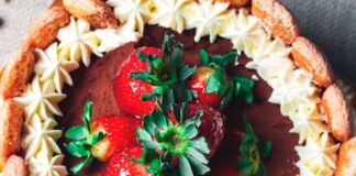 Top view of a chocolate cake garnished with fresh strawberries and whipped cream, creating a delightful dessert.