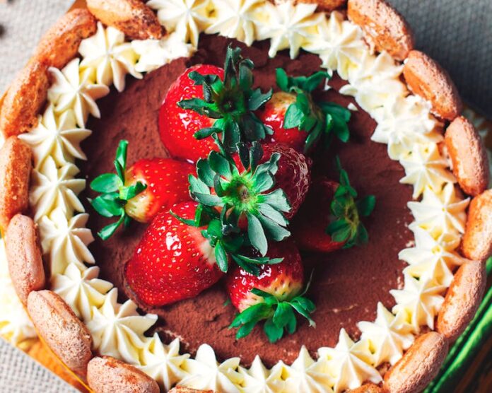 Descubra a História Fascinante do Charlotte Russe e Surpreenda-se Top view of a chocolate cake garnished with fresh strawberries and whipped cream, creating a delightful dessert.