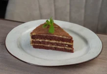 Bolo de Chocolate com Menta A tempting chocolate layer cake slice with mint garnish on a white plate.