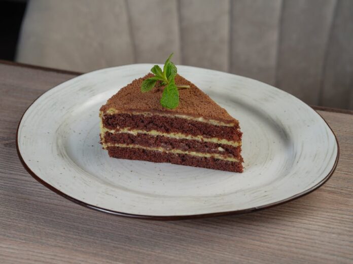 Descubra o Bolo de Chocolate com Menta Mais Irresistível A tempting chocolate layer cake slice with mint garnish on a white plate.