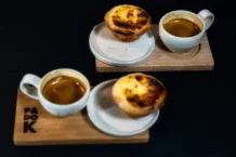Descubra o doce tradicional português económico e surpreenda Enjoy authentic Portuguese Pastel de Nata paired with espresso at a Berlin café, perfect for dessert lovers.